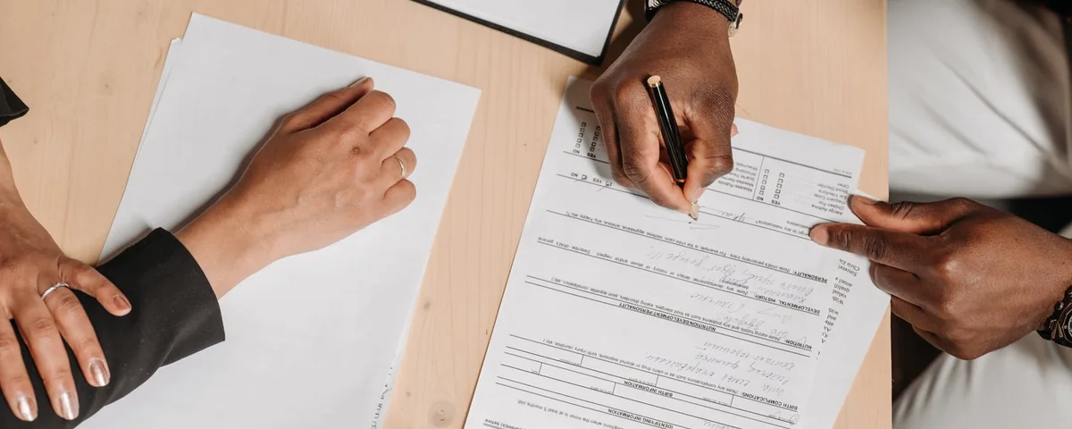 Deux personnes signant des documents officiels sur une table