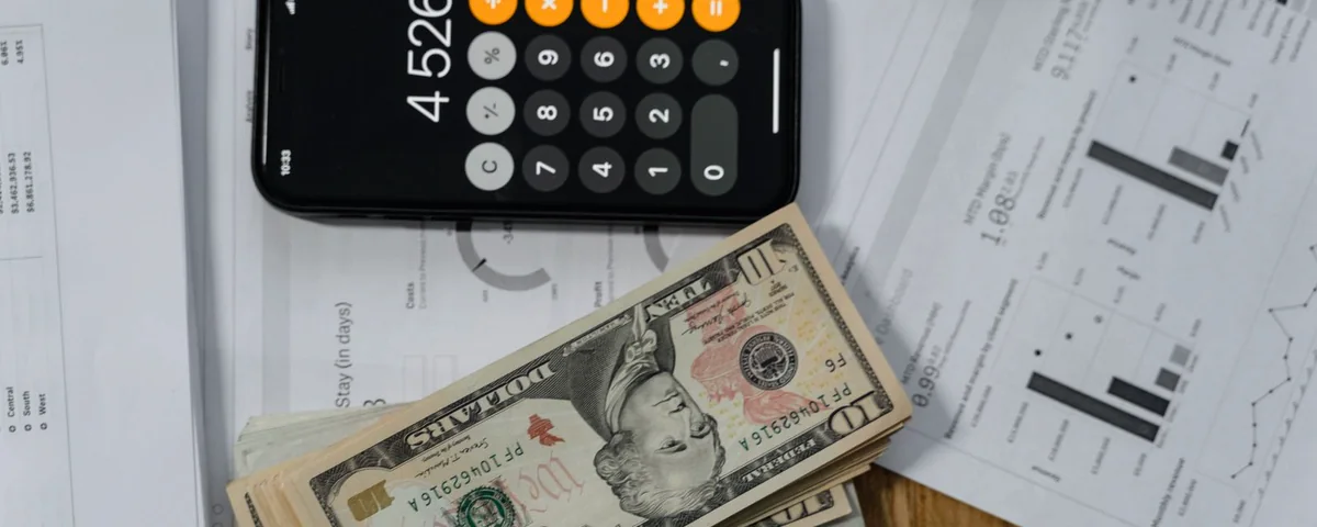 A calculator, banknotes and costing documents on a desk, used to work out the real cost of an import