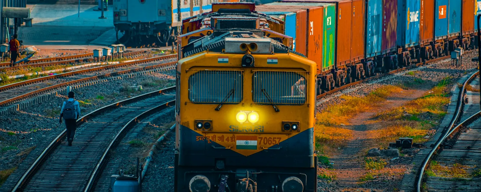 Tren de mercancías cargado con contenedores sobre las vías al atardecer